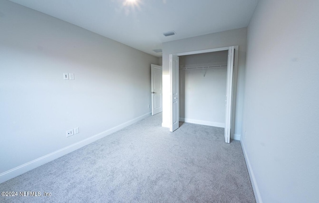 unfurnished bedroom featuring light colored carpet and a closet