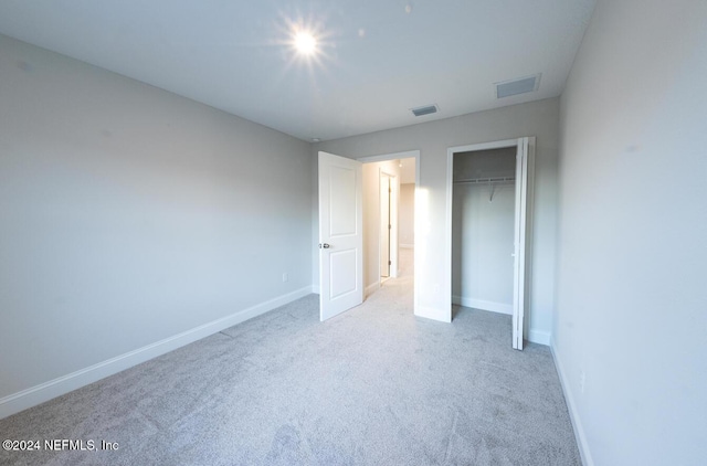 unfurnished bedroom featuring light colored carpet and a closet