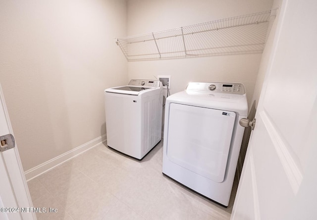 clothes washing area with washer and clothes dryer and light tile patterned floors