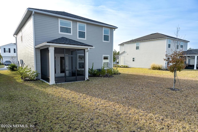 rear view of house featuring a lawn and a sunroom