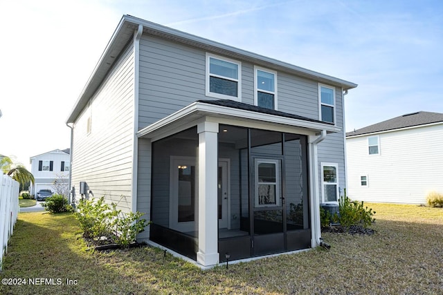 rear view of property with a lawn and a sunroom