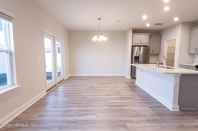 kitchen featuring plenty of natural light, stainless steel fridge with ice dispenser, sink, and light hardwood / wood-style flooring