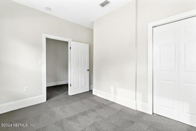 unfurnished bedroom with light colored carpet and a closet