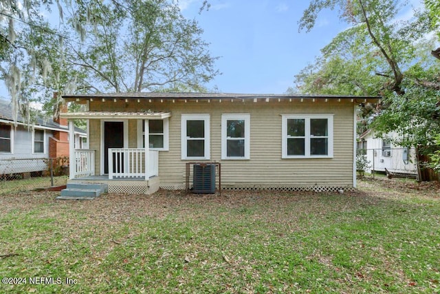 rear view of property featuring a lawn and cooling unit