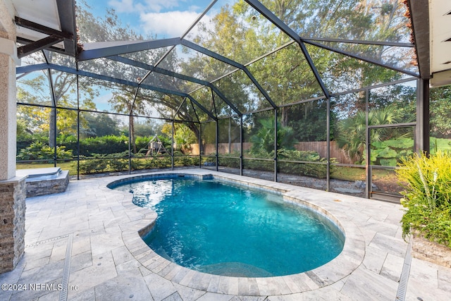 view of swimming pool featuring glass enclosure and a patio