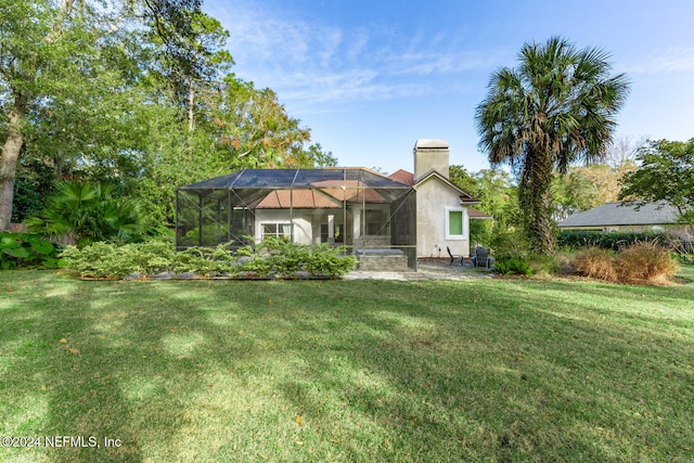 rear view of property with a lanai and a yard