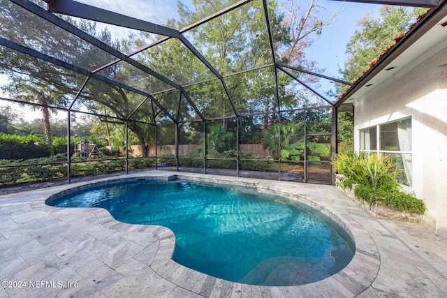 view of pool with glass enclosure and a patio area