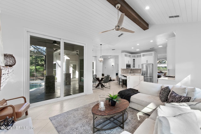 tiled living room with ceiling fan, lofted ceiling with beams, and sink