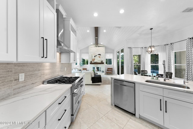 kitchen with appliances with stainless steel finishes, wall chimney range hood, pendant lighting, white cabinetry, and lofted ceiling