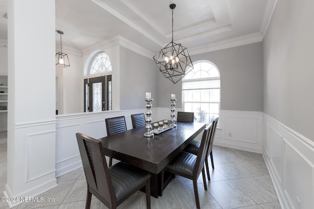 tiled dining space featuring a raised ceiling, crown molding, and a chandelier