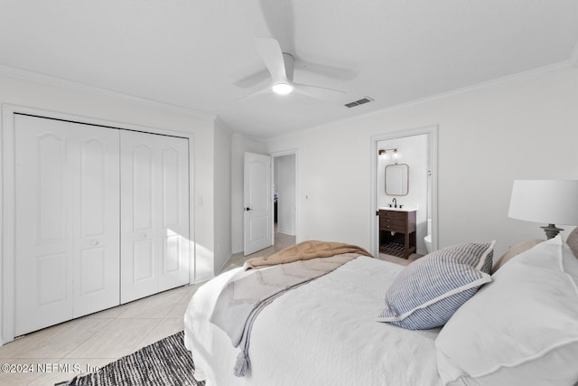 bedroom featuring crown molding, ensuite bath, ceiling fan, light tile patterned floors, and a closet