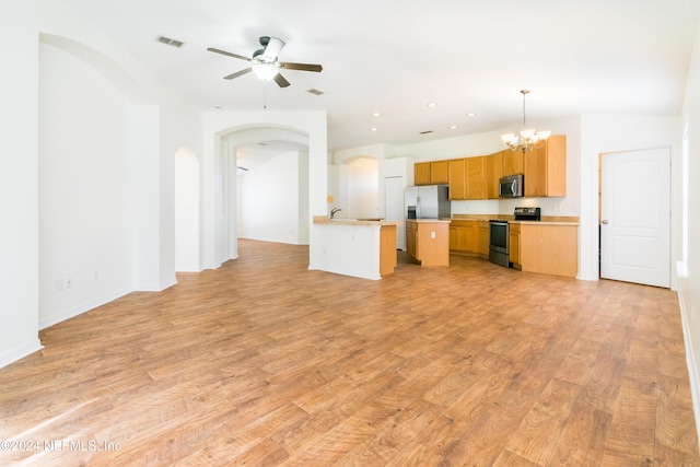 kitchen with appliances with stainless steel finishes, ceiling fan with notable chandelier, pendant lighting, light hardwood / wood-style flooring, and a kitchen island