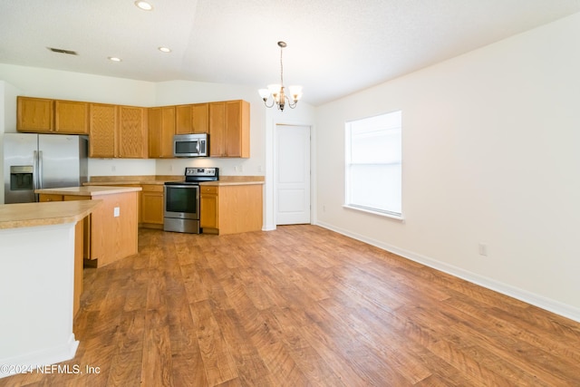 kitchen featuring appliances with stainless steel finishes, decorative light fixtures, a notable chandelier, light hardwood / wood-style floors, and lofted ceiling