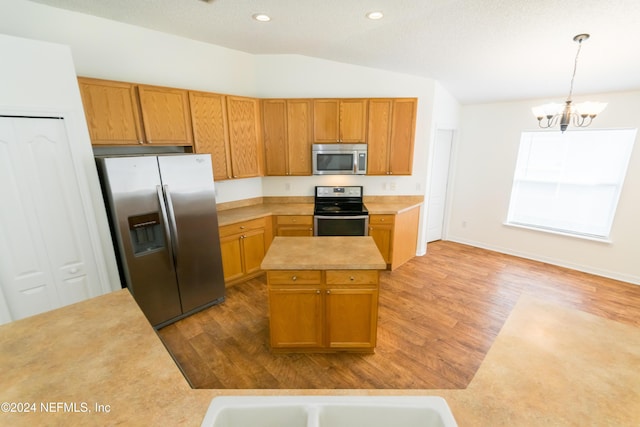 kitchen with stainless steel appliances, vaulted ceiling, pendant lighting, an inviting chandelier, and a kitchen island