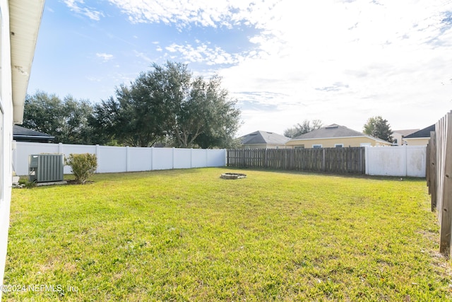 view of yard with central AC and an outdoor fire pit