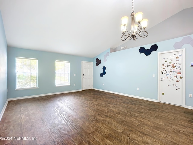 spare room with lofted ceiling, dark wood-type flooring, and a chandelier