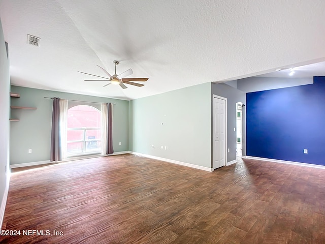 empty room with a textured ceiling, lofted ceiling, ceiling fan, and dark wood-type flooring