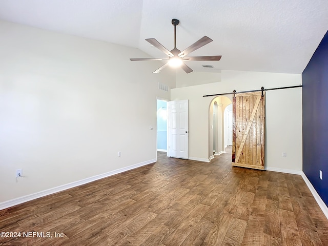 empty room with a barn door, ceiling fan, high vaulted ceiling, and hardwood / wood-style flooring