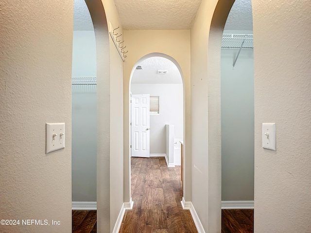 hallway featuring a textured ceiling and dark hardwood / wood-style floors