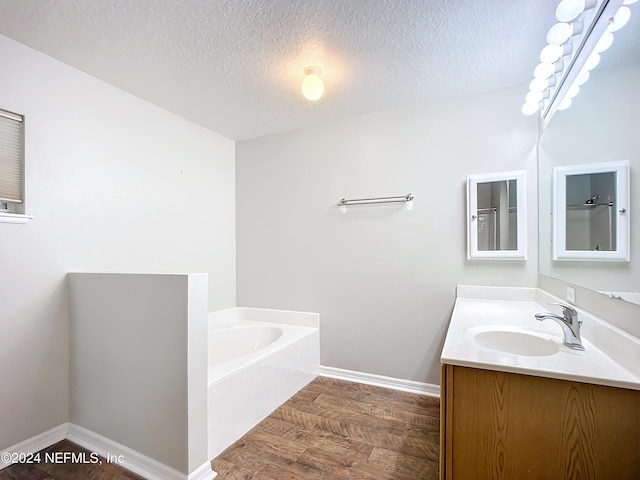 bathroom featuring a textured ceiling, vanity, hardwood / wood-style flooring, and a bathtub