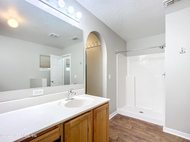 bathroom with hardwood / wood-style flooring, vanity, a textured ceiling, and walk in shower