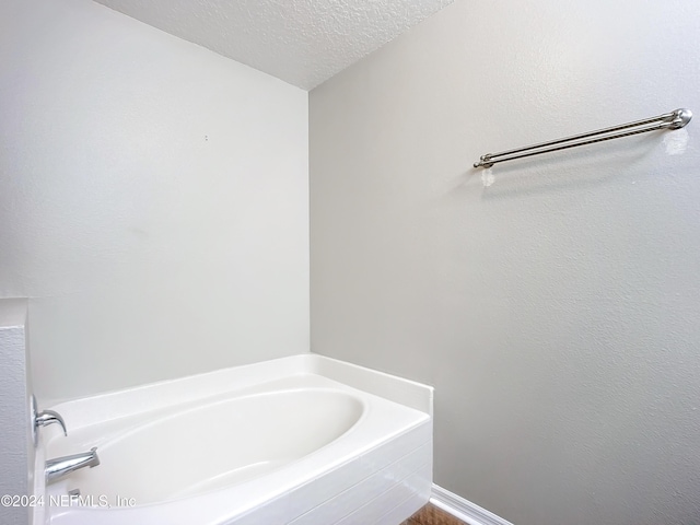 bathroom with a bathing tub and a textured ceiling