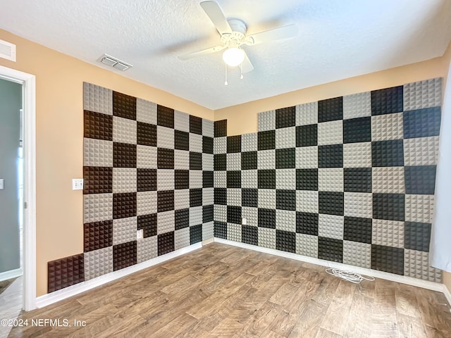 empty room with ceiling fan, hardwood / wood-style floors, and a textured ceiling