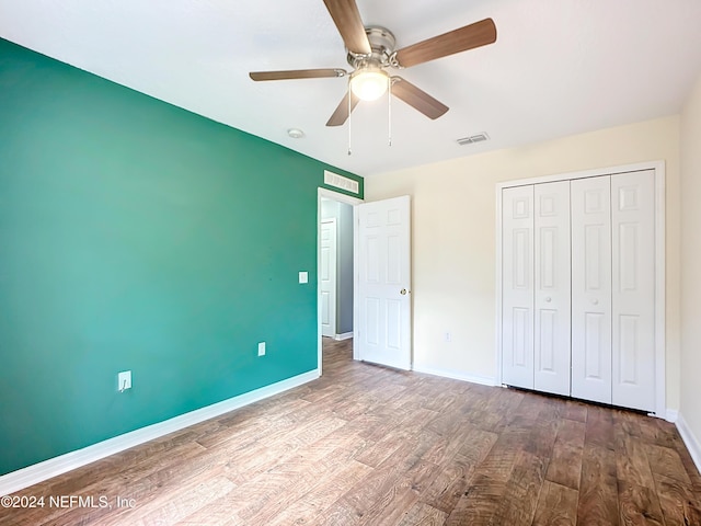 unfurnished bedroom featuring ceiling fan, a closet, and hardwood / wood-style flooring