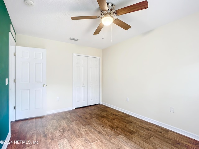 unfurnished bedroom with ceiling fan, wood-type flooring, and a closet