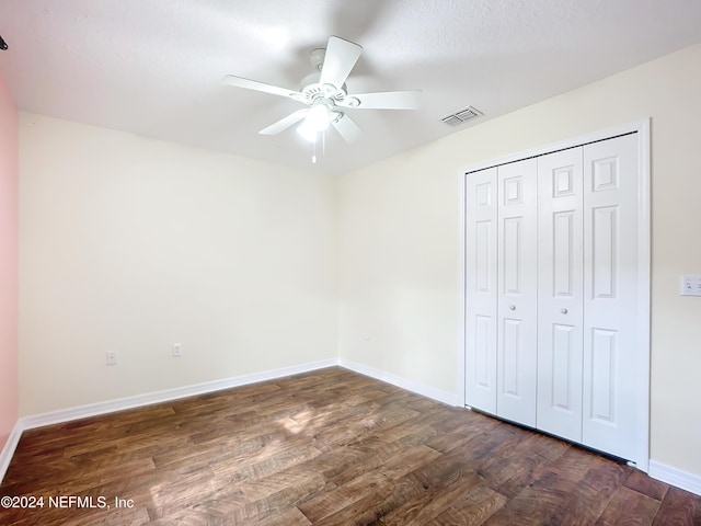 unfurnished bedroom with a closet, dark hardwood / wood-style floors, and ceiling fan