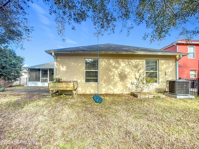 rear view of property with a lawn, a sunroom, and cooling unit