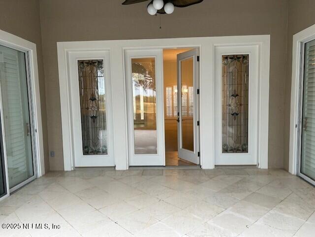 unfurnished sunroom featuring ceiling fan and french doors