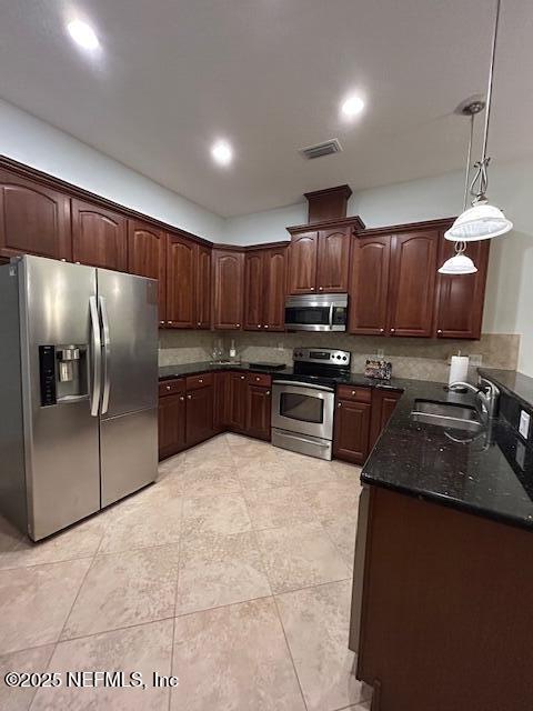 kitchen with sink, hanging light fixtures, dark stone countertops, light tile patterned floors, and stainless steel appliances