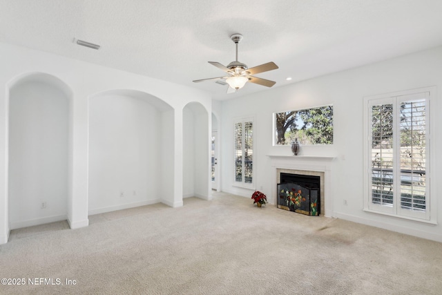 unfurnished living room with a tile fireplace, ceiling fan, light carpet, and a textured ceiling