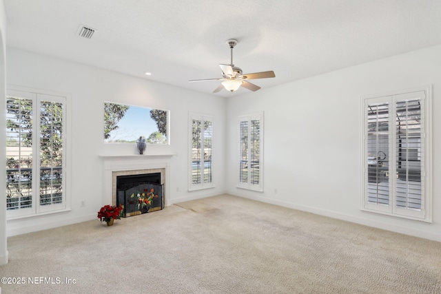 unfurnished living room featuring a tile fireplace, light carpet, and ceiling fan