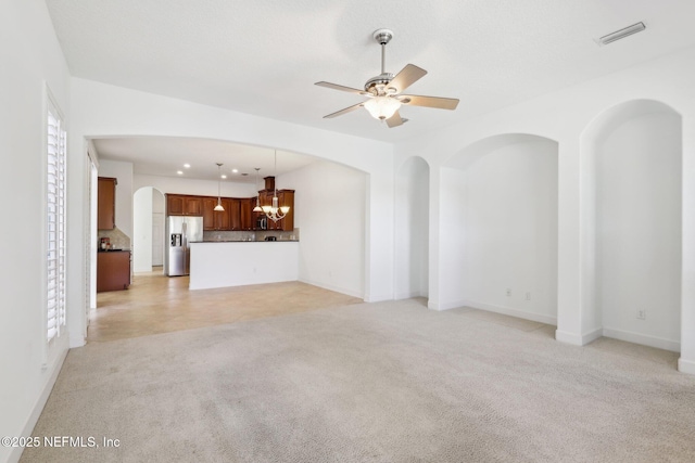 unfurnished living room with ceiling fan with notable chandelier