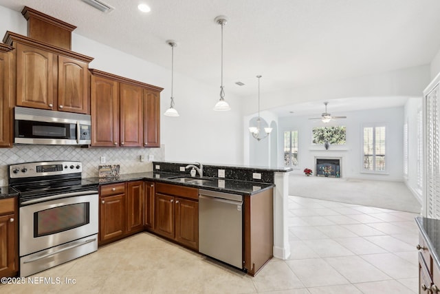 kitchen with light carpet, ceiling fan with notable chandelier, stainless steel appliances, sink, and decorative light fixtures