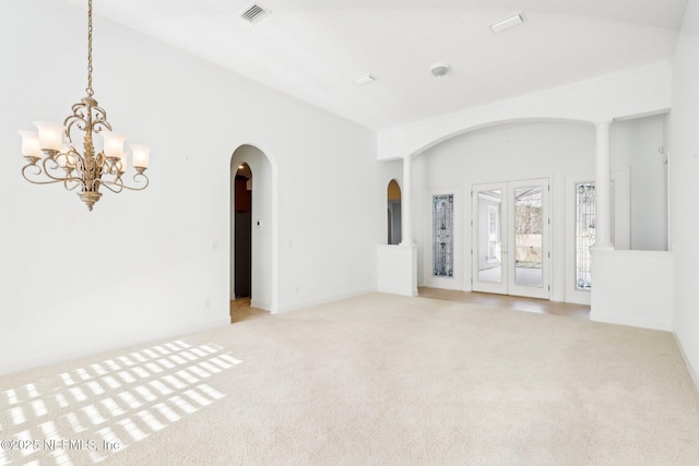 carpeted spare room with an inviting chandelier