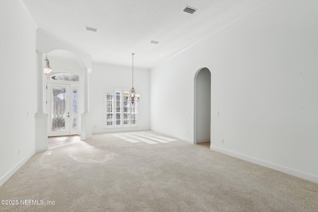 carpeted empty room with a chandelier, french doors, and ornamental molding