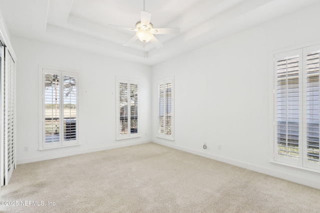 carpeted empty room featuring a tray ceiling and ceiling fan