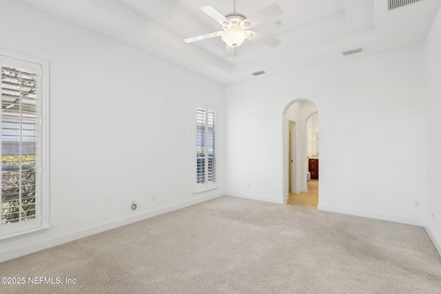 carpeted empty room with a raised ceiling and ceiling fan