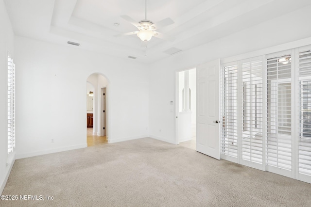 unfurnished bedroom with access to exterior, ceiling fan, light colored carpet, and a tray ceiling