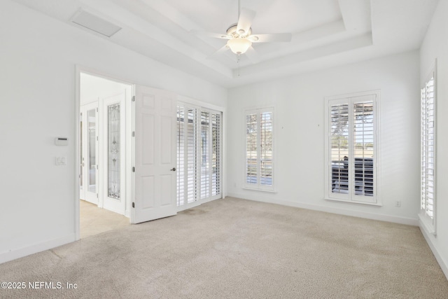 carpeted empty room with a raised ceiling and ceiling fan