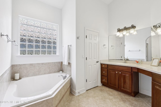 bathroom featuring tile patterned flooring, vanity, tiled bath, and a wealth of natural light