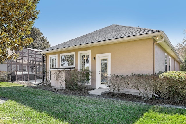 rear view of property featuring a lawn and a lanai