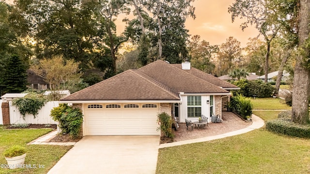 single story home featuring a garage and a yard