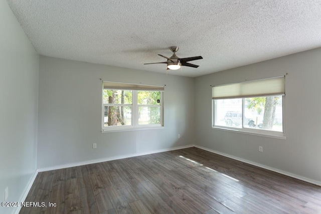 empty room featuring a healthy amount of sunlight, a textured ceiling, and dark wood-type flooring