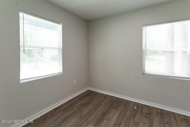 empty room featuring dark wood-type flooring and a textured ceiling