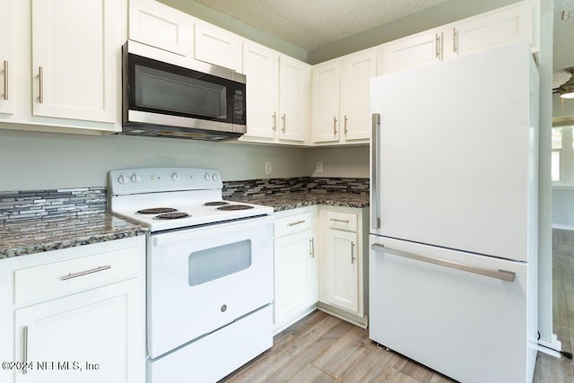 kitchen featuring light wood-type flooring, a textured ceiling, white appliances, and white cabinetry