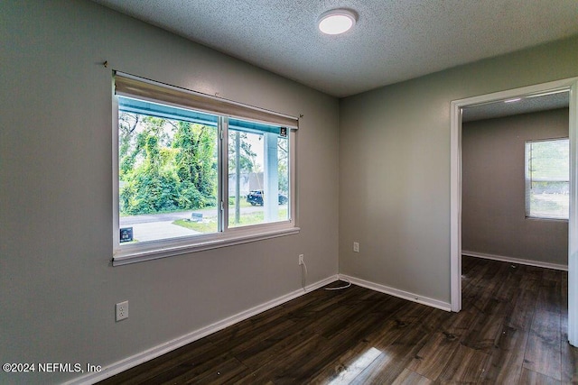 empty room with a textured ceiling and dark hardwood / wood-style floors